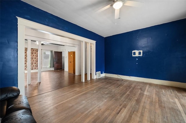 unfurnished living room with a ceiling fan, hardwood / wood-style floors, visible vents, and baseboards