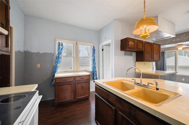 kitchen with a sink, pendant lighting, ceiling fan, light countertops, and dark wood-style floors