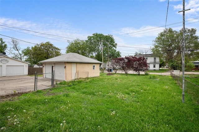 view of yard featuring fence, a detached garage, and an outbuilding
