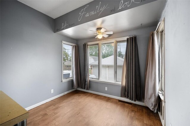 unfurnished room featuring ceiling fan, baseboards, visible vents, and wood finished floors