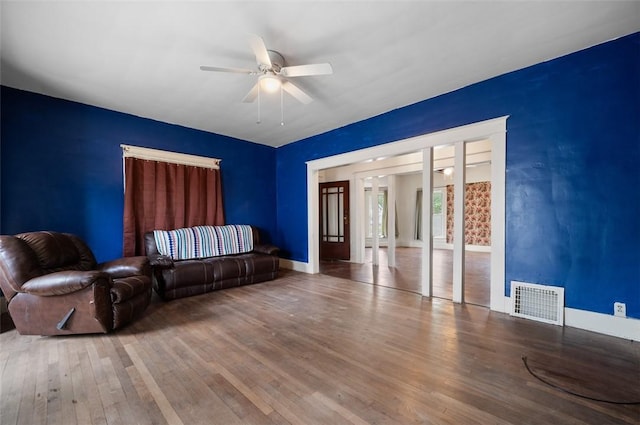 living area with baseboards, a ceiling fan, visible vents, and wood finished floors