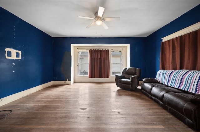 living area with wood finished floors, baseboards, and ceiling fan