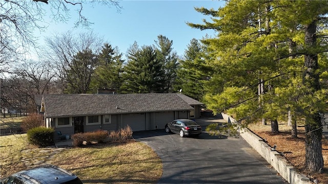 single story home with aphalt driveway and an attached garage