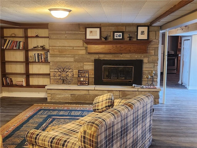 living area with baseboards, a stone fireplace, and wood finished floors