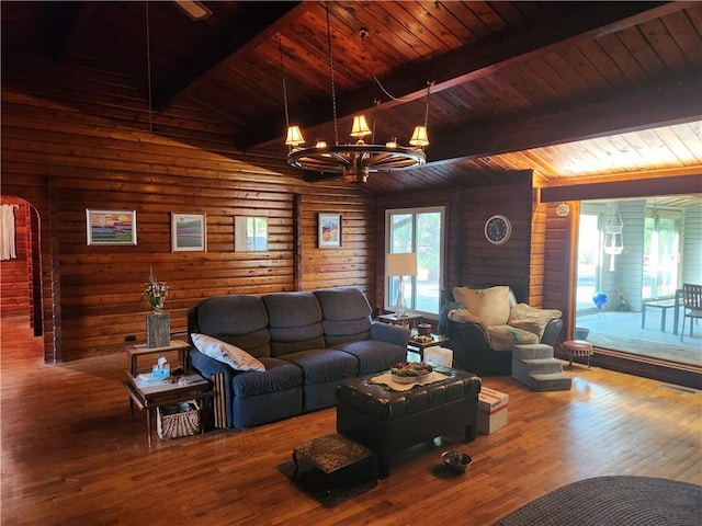 living area with lofted ceiling with beams, rustic walls, wood-type flooring, wooden ceiling, and a chandelier