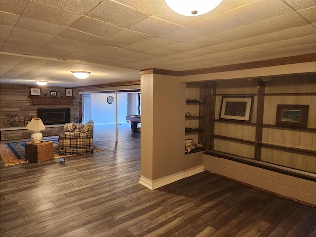 basement featuring a stone fireplace and dark wood-style floors