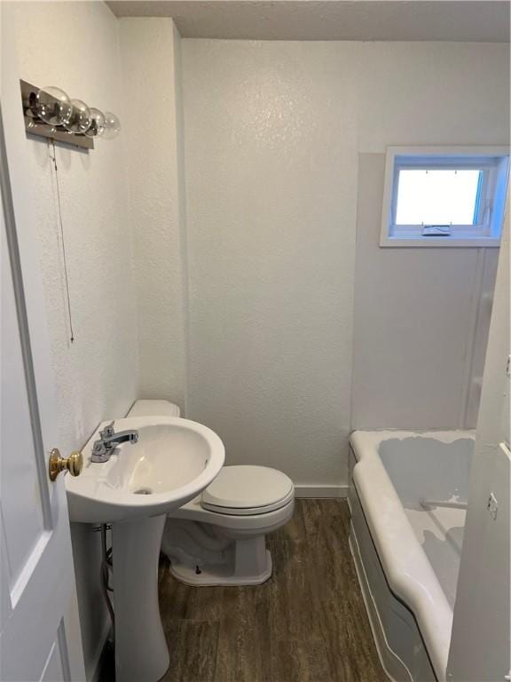 bathroom featuring a bathing tub, toilet, and wood-type flooring