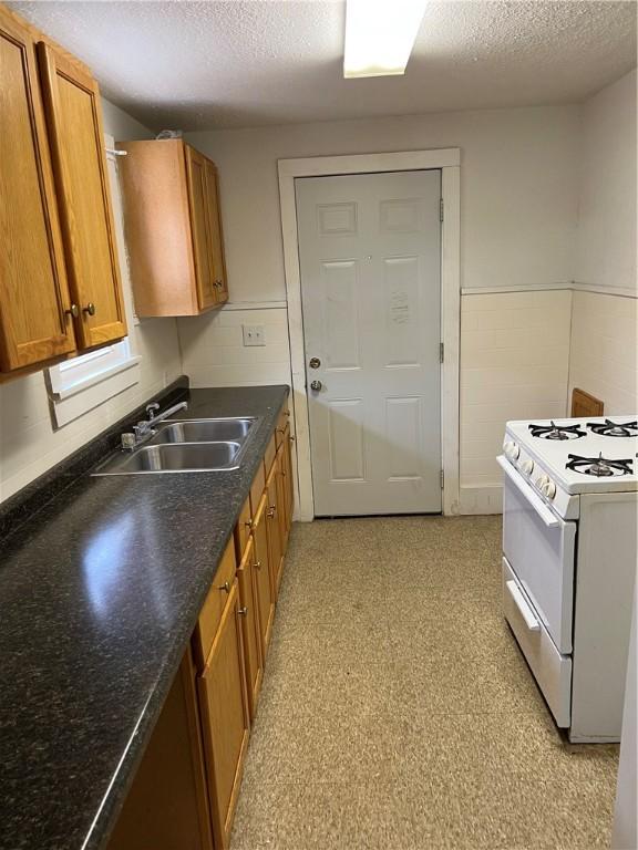 kitchen with white stove, sink, and a textured ceiling