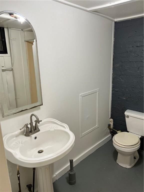 bathroom featuring concrete flooring, toilet, and sink