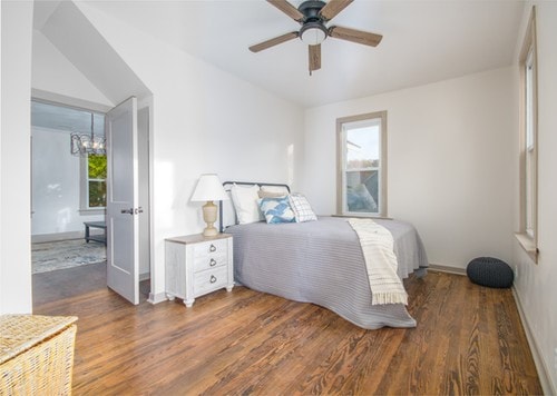 bedroom with ceiling fan with notable chandelier and dark wood-type flooring