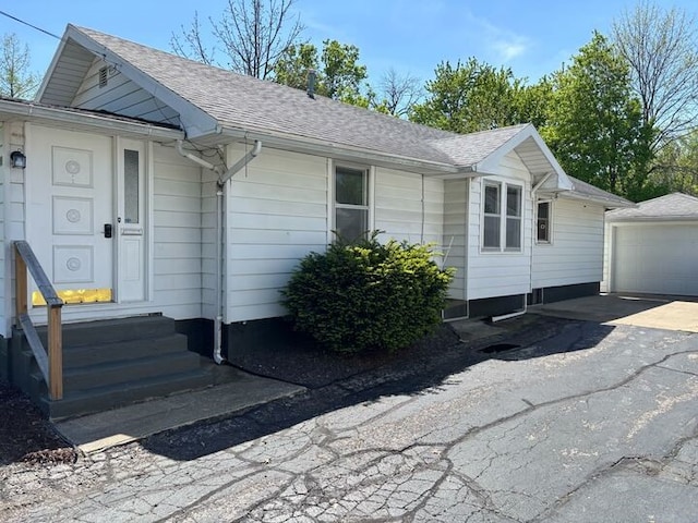 811 N Jefferson St, Robinson, IL 62454 - view of front of house featuring entry steps, an outbuilding, a detached garage, roof with shingles, and asphalt driveway