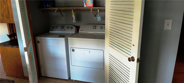 clothes washing area with independent washer and dryer and light tile patterned floors