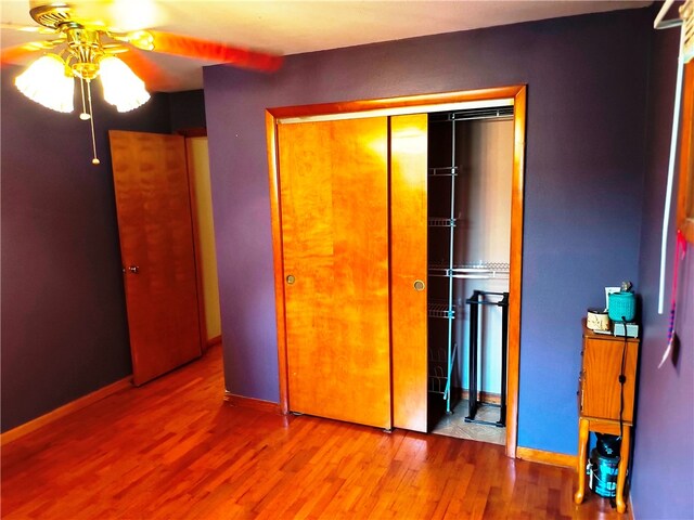 unfurnished bedroom featuring hardwood / wood-style floors, a closet, and ceiling fan