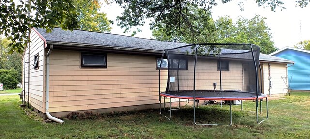 back of property with a lawn and a trampoline