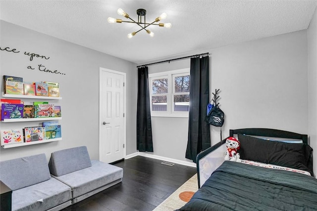 bedroom featuring a chandelier, a textured ceiling, baseboards, and wood finished floors