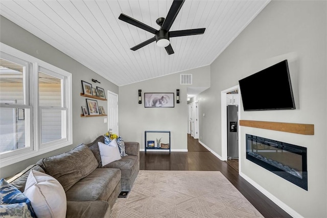 living room with baseboards, visible vents, a glass covered fireplace, lofted ceiling, and wood finished floors