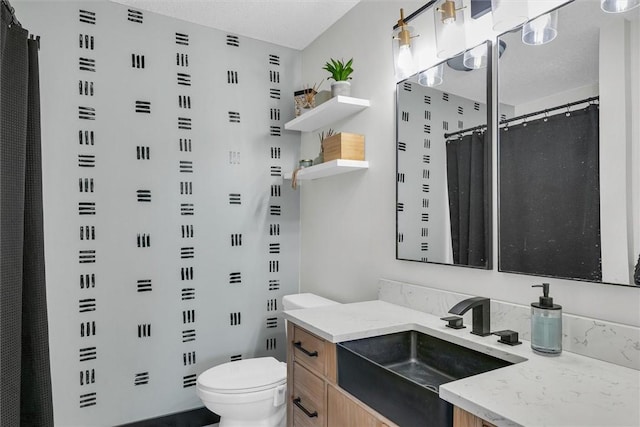 full bathroom featuring toilet, a textured ceiling, and vanity