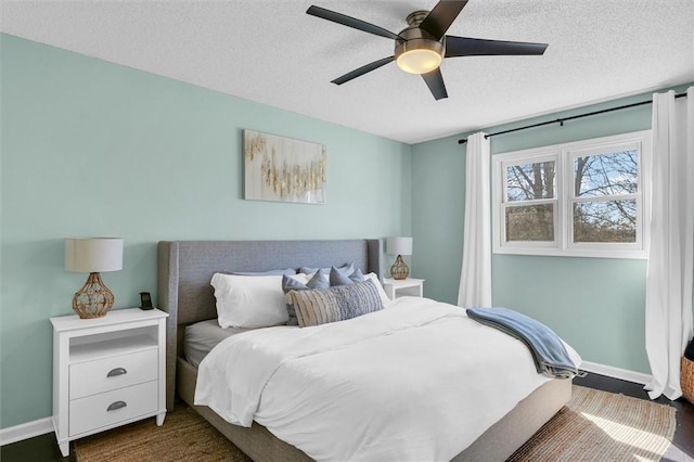 bedroom featuring a ceiling fan, baseboards, dark wood finished floors, and a textured ceiling