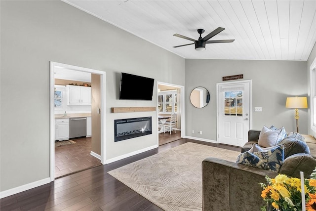 living room featuring lofted ceiling, baseboards, dark wood finished floors, and a ceiling fan