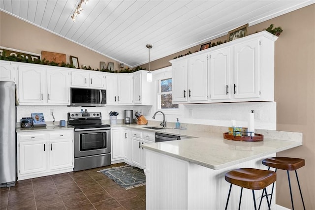 kitchen with lofted ceiling, a peninsula, a sink, white cabinetry, and appliances with stainless steel finishes