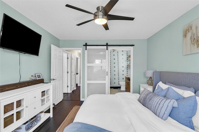 bedroom featuring a barn door, dark wood-type flooring, ceiling fan, a textured ceiling, and ensuite bath