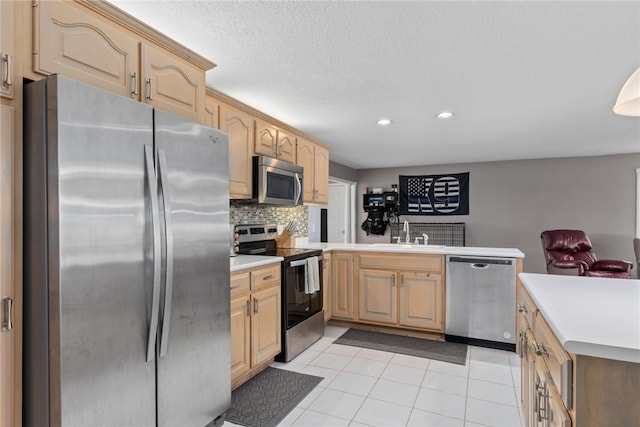 kitchen featuring decorative backsplash, a peninsula, recessed lighting, light countertops, and appliances with stainless steel finishes