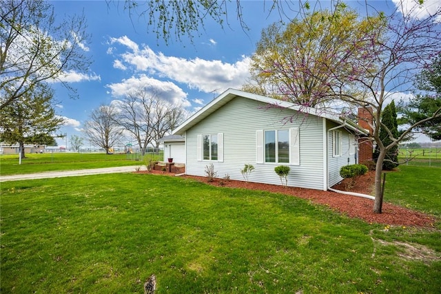 view of property exterior with fence, a yard, a chimney, an attached garage, and driveway