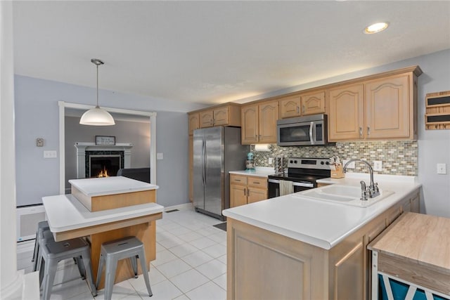 kitchen featuring appliances with stainless steel finishes, tasteful backsplash, a sink, light countertops, and a peninsula