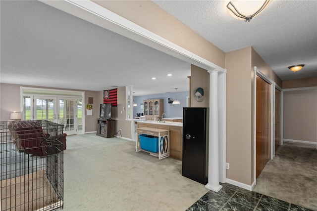 hallway with a sink, baseboards, a textured ceiling, and light colored carpet
