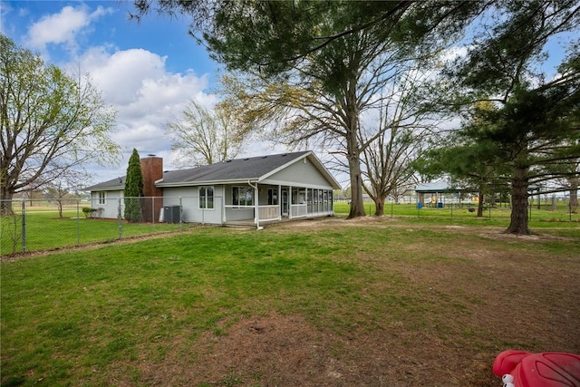 rear view of house featuring fence, a sunroom, a chimney, cooling unit, and a yard