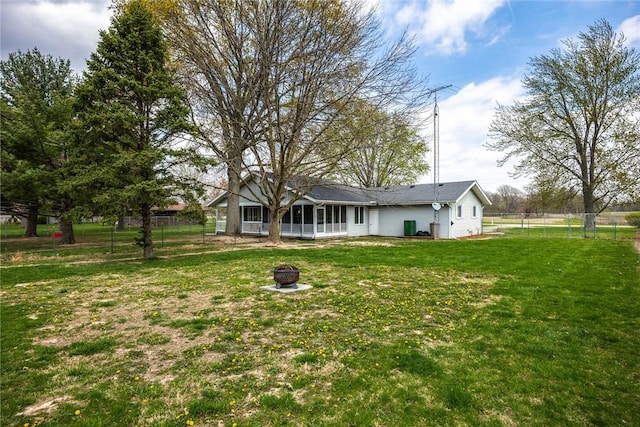rear view of property featuring a yard, fence, and a fire pit