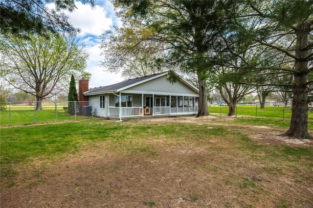 rear view of property with fence, a chimney, a sunroom, central air condition unit, and a yard