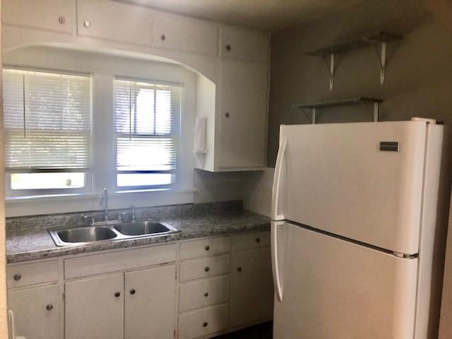 906 S 3rd St, Effingham, IL 62401 - kitchen with freestanding refrigerator, white cabinetry, and arched walkways
