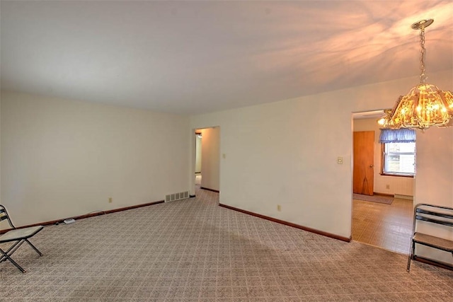 carpeted empty room featuring a chandelier