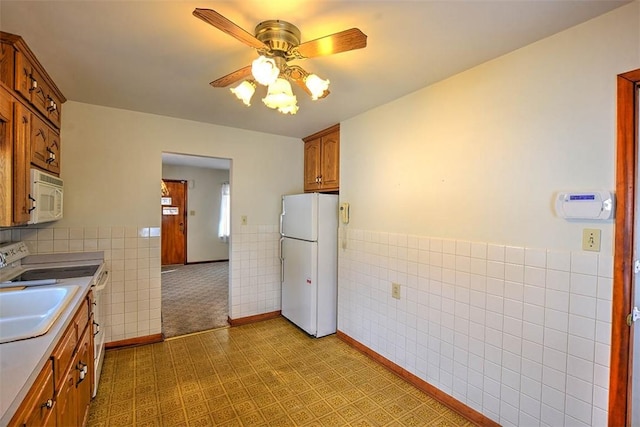 kitchen featuring ceiling fan, white appliances, sink, and tile walls