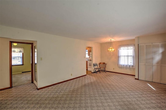 unfurnished room featuring carpet and a notable chandelier