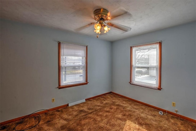 carpeted spare room featuring baseboard heating, ceiling fan, and a healthy amount of sunlight