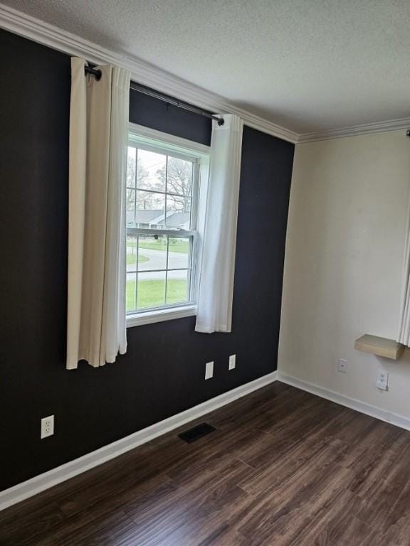 empty room with visible vents, ornamental molding, baseboards, a textured ceiling, and dark wood-style flooring