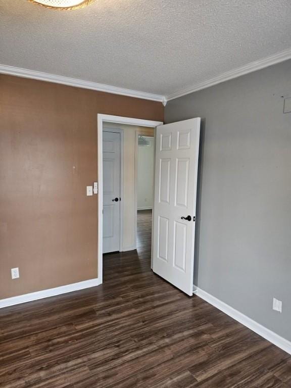empty room featuring ornamental molding, baseboards, dark wood-style flooring, and a textured ceiling