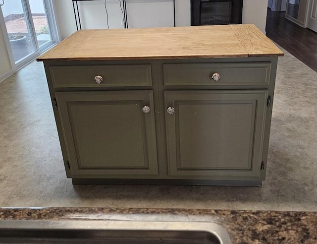 room details featuring gray cabinets, baseboards, a kitchen island, wood counters, and carpet floors