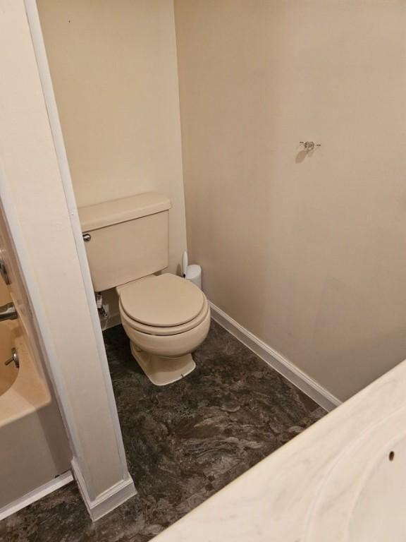 full bath featuring a bath, toilet, and baseboards