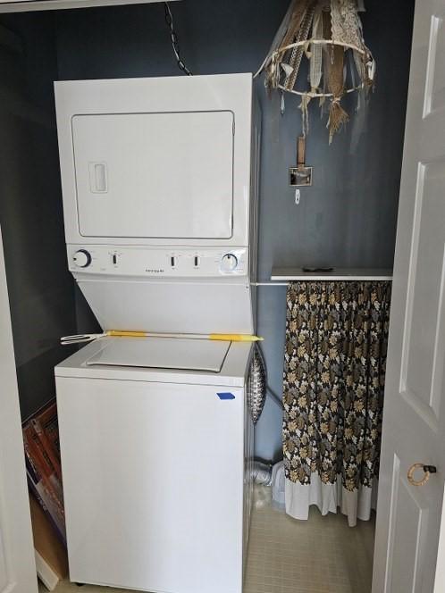 laundry area featuring tile patterned flooring, stacked washing maching and dryer, and laundry area