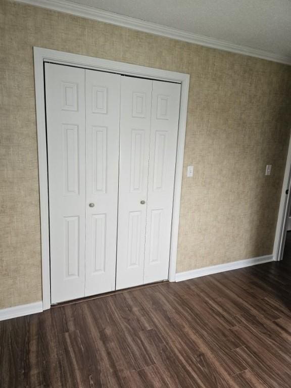 unfurnished bedroom featuring baseboards, dark wood-type flooring, and ornamental molding