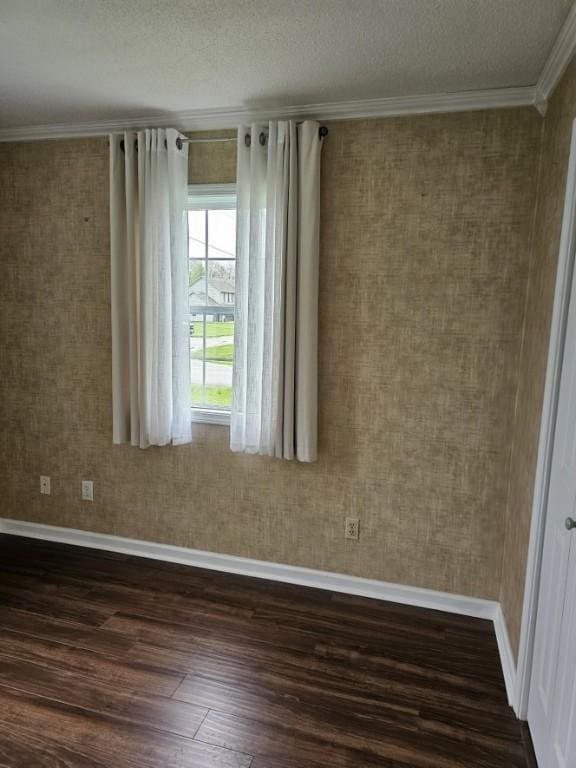 unfurnished room featuring dark wood finished floors, a textured ceiling, baseboards, and ornamental molding
