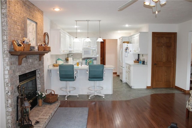 interior space with hardwood / wood-style floors, a brick fireplace, baseboards, and a ceiling fan