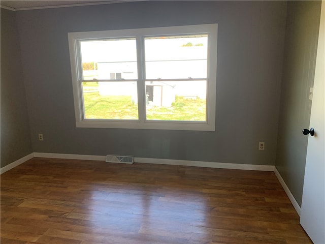 unfurnished room featuring plenty of natural light, dark wood-type flooring, and ornamental molding