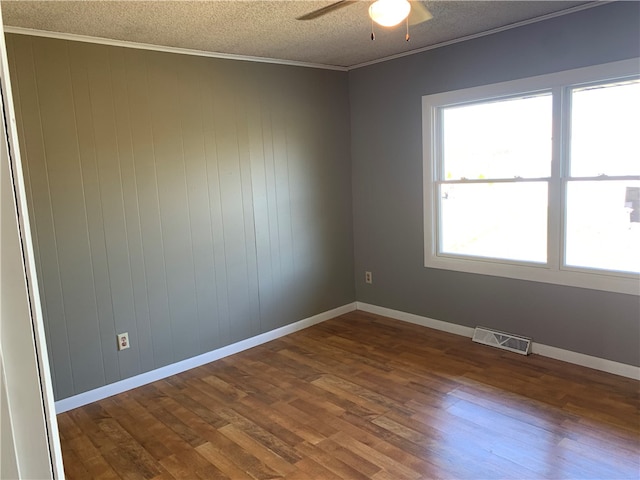 unfurnished room with crown molding, dark hardwood / wood-style flooring, a textured ceiling, and wooden walls