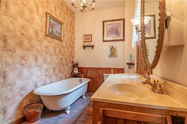 bathroom with wood walls, vanity, a bath, and an inviting chandelier