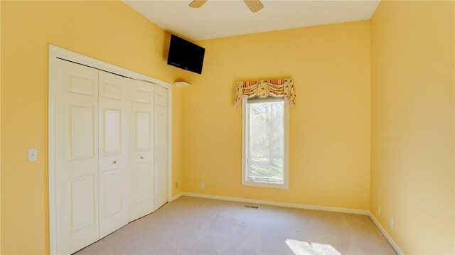 unfurnished bedroom with carpet, baseboards, ceiling fan, and a closet