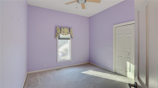 spare room featuring a ceiling fan, carpet, and baseboards